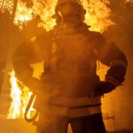 a firefighter standing in front of a large fire